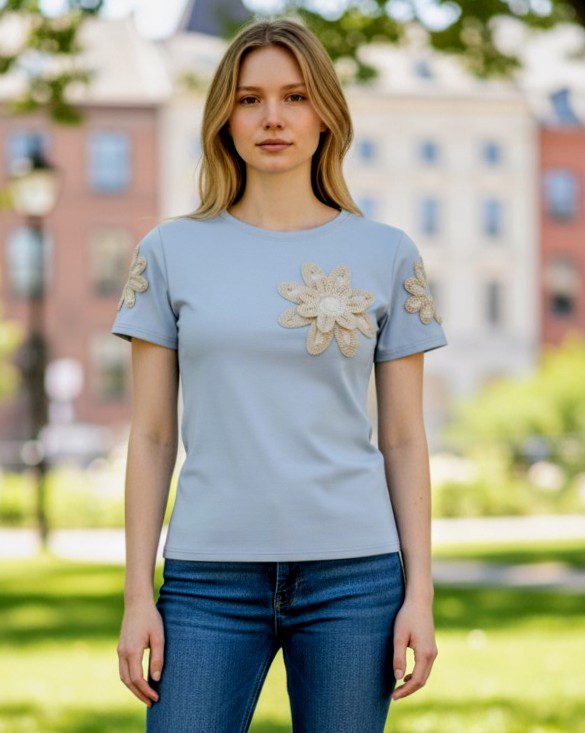 Modelo a usar a t-shirt azul com flor de croché, estilo casual.
