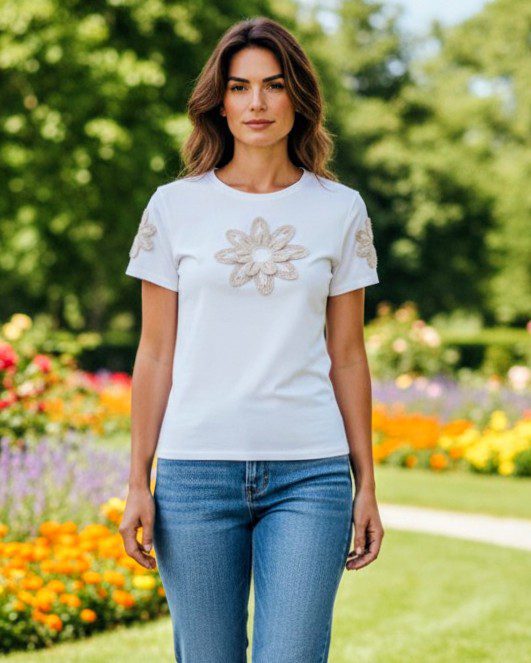 Modelo a usar a t-shirt branca com flor de croché, look delicado.