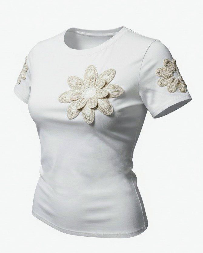 Detalhe da flor de croché na t-shirt branca, com textura artesanal.